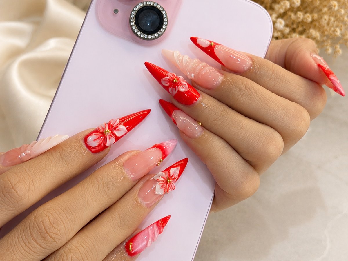 Bold red stiletto nails with sculpted white flower art